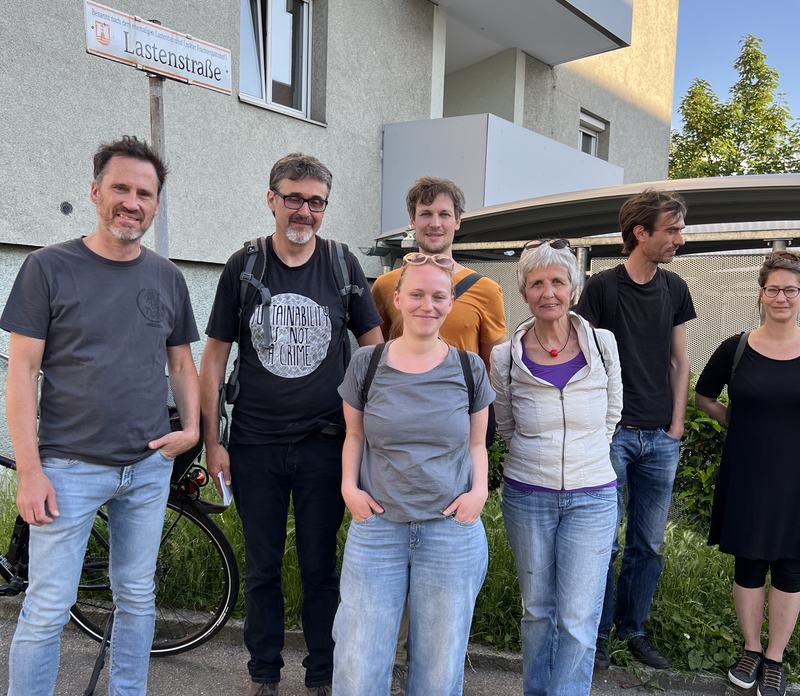 Helge Langer mit sechs Teilnehmenden eines Gehrundgangs im Linzer Franckviertel, daneben das Straßenschild Lastenstraße
