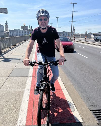 Helge Langer fährt mit Helm auf einem rot markierten Streifen am Rand der Nibelungenbrücke, daneben die Fahrbahn mit Autos